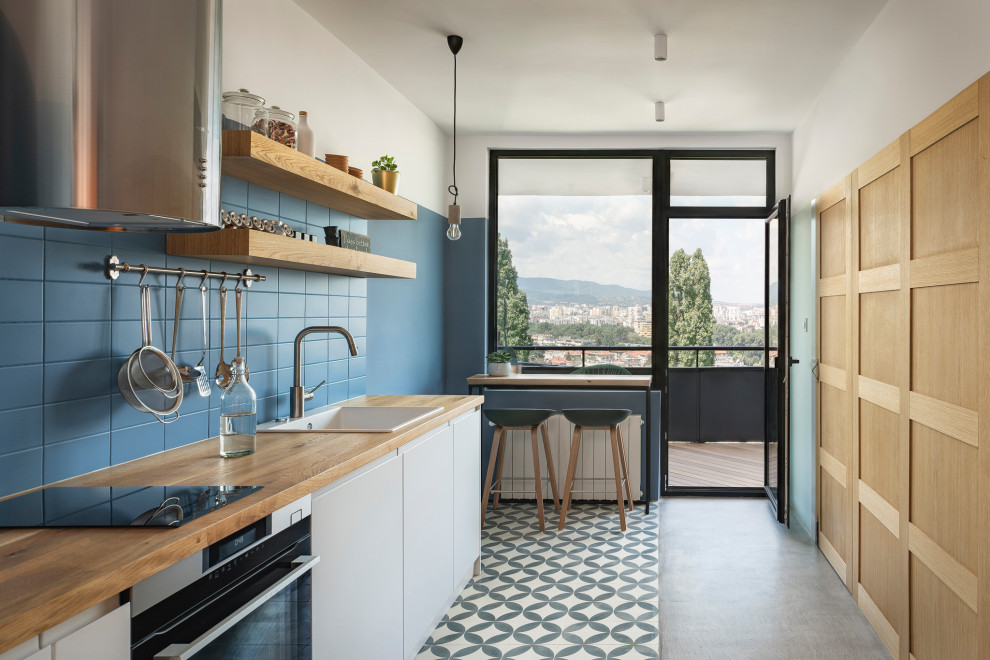 Inspiration for a contemporary single-wall separate kitchen in London with a drop-in sink, flat-panel cabinets, white cabinets, wood benchtops, blue splashback, stainless steel appliances, no island, multi-coloured floor and beige benchtop.