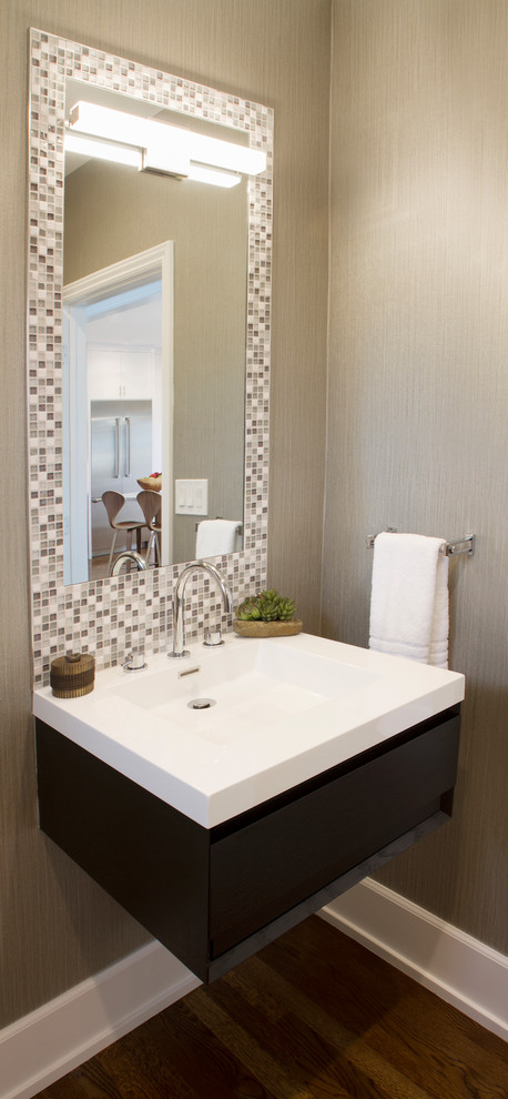 This is an example of a beach style powder room with multi-coloured tile, mosaic tile, grey walls, medium hardwood floors, an integrated sink, laminate benchtops, brown floor, white benchtops, flat-panel cabinets and dark wood cabinets.
