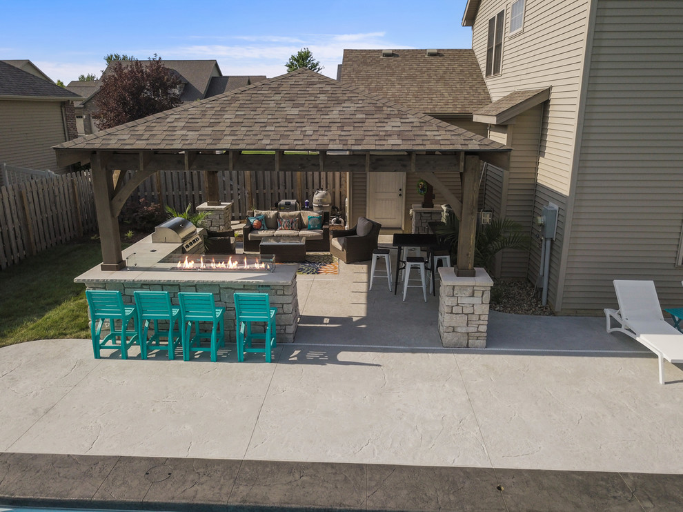 This is an example of a mid-sized beach style backyard patio in Chicago with stamped concrete.