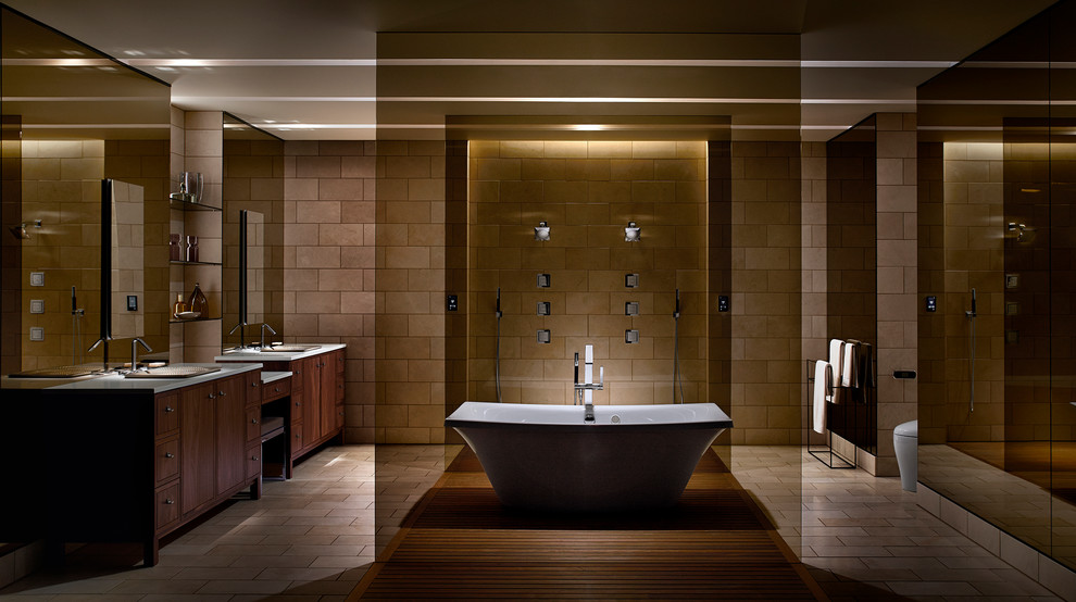 Design ideas for an expansive contemporary master bathroom in Salt Lake City with flat-panel cabinets, dark wood cabinets, a freestanding tub, an alcove shower, a one-piece toilet, beige tile, ceramic tile, beige walls, ceramic floors, a drop-in sink and solid surface benchtops.