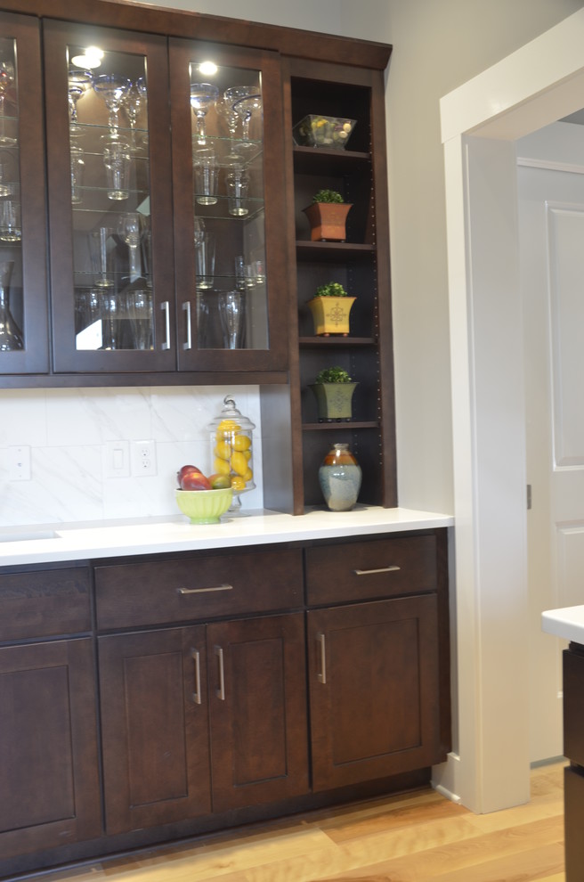 Home design - large transitional u-shaped light wood floor home design idea with an undermount sink, shaker cabinets, dark wood cabinets, quartz countertops, white backsplash, stone tile backsplash, stainless steel appliances and an island