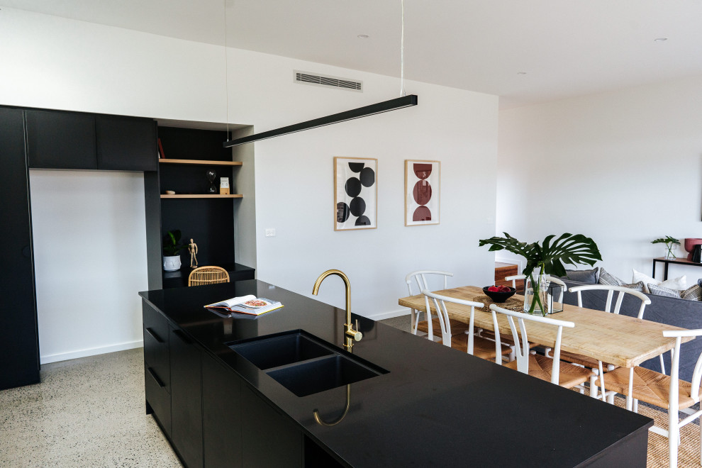 This is an example of a mid-sized modern galley open plan kitchen in Wollongong with an undermount sink, flat-panel cabinets, black cabinets, quartz benchtops, black splashback, ceramic splashback, stainless steel appliances, concrete floors, with island, grey floor and black benchtop.