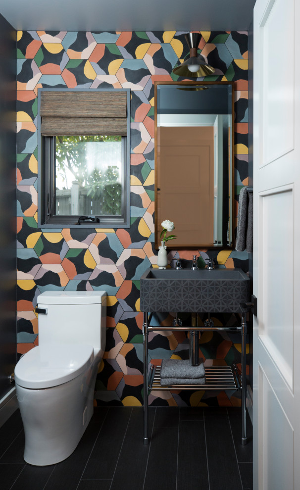 Inspiration för mellanstora moderna toaletter, med öppna hyllor, en toalettstol med hel cisternkåpa, flerfärgad kakel, cementkakel, svarta väggar, klinkergolv i porslin, ett konsol handfat och svart golv