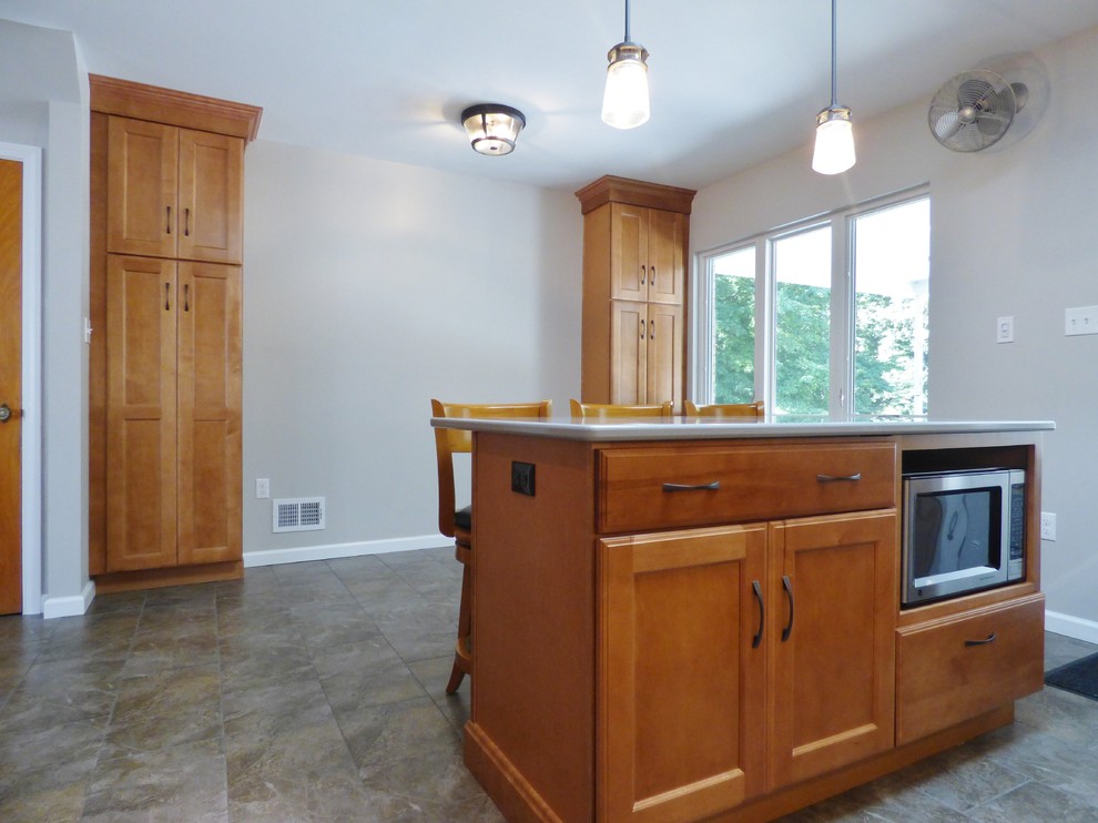 Transitional l-shaped porcelain tile eat-in kitchen photo with an undermount sink, recessed-panel cabinets, medium tone wood cabinets, quartz countertops, white backsplash, subway tile backsplash, stainless steel appliances and an island