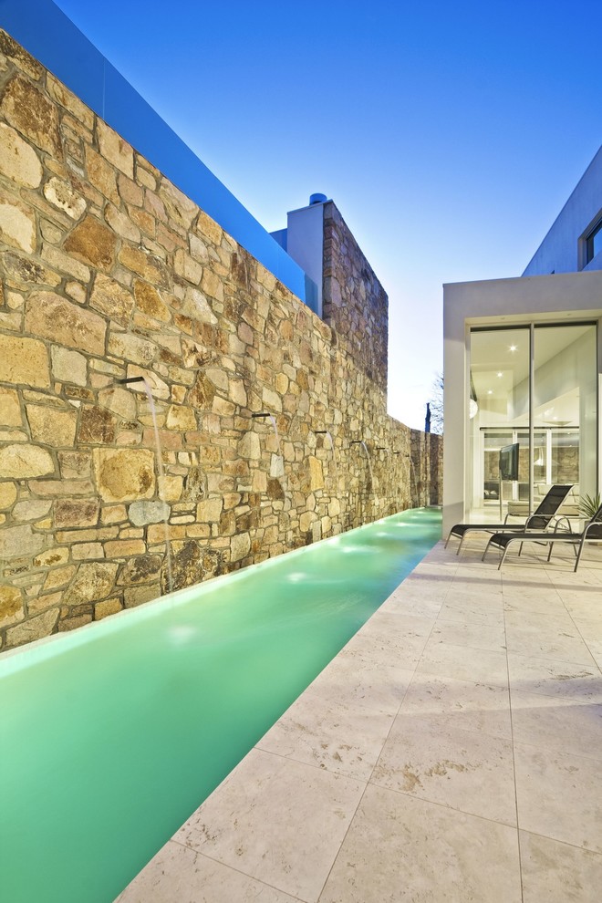 Design ideas for a small contemporary side yard custom-shaped lap pool in Melbourne with natural stone pavers.