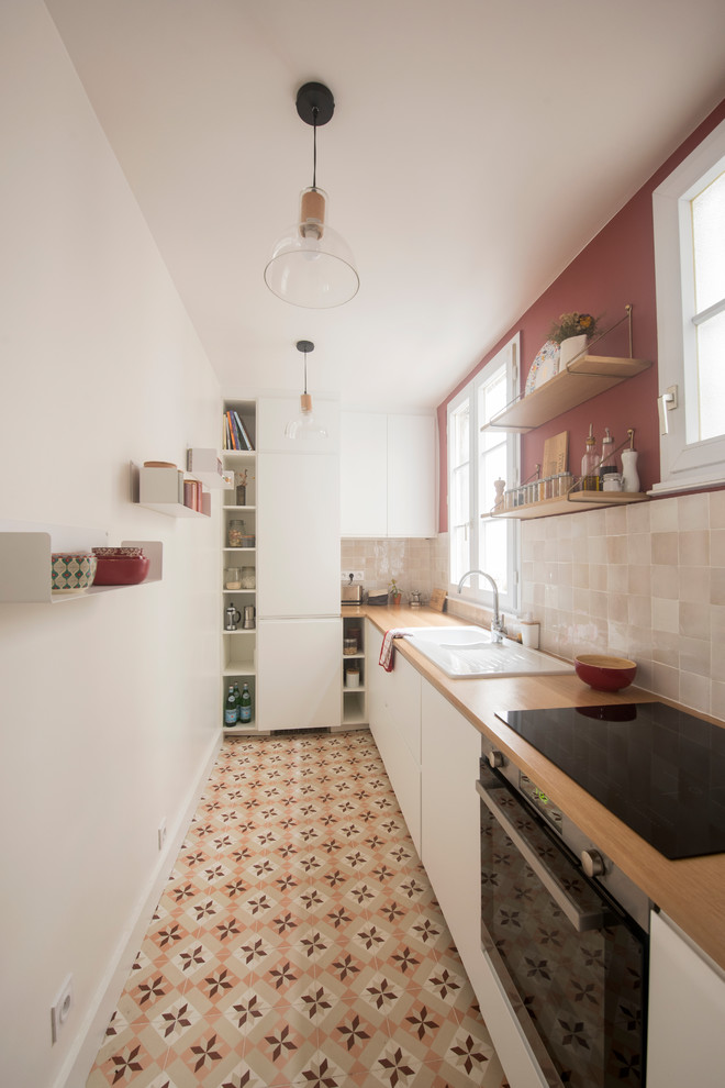 This is an example of a mid-sized midcentury l-shaped separate kitchen in Paris with a double-bowl sink, white cabinets, wood benchtops, beige splashback, terra-cotta splashback, panelled appliances, cement tiles, no island, multi-coloured floor and brown benchtop.