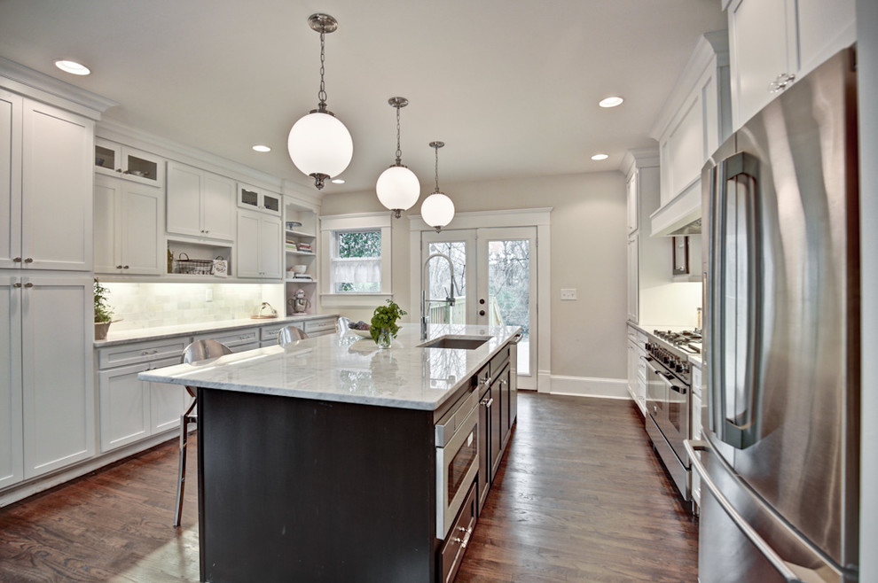 Design ideas for a mid-sized arts and crafts u-shaped eat-in kitchen in Atlanta with an undermount sink, shaker cabinets, white cabinets, marble benchtops, grey splashback, stone tile splashback, stainless steel appliances, dark hardwood floors, with island and brown floor.