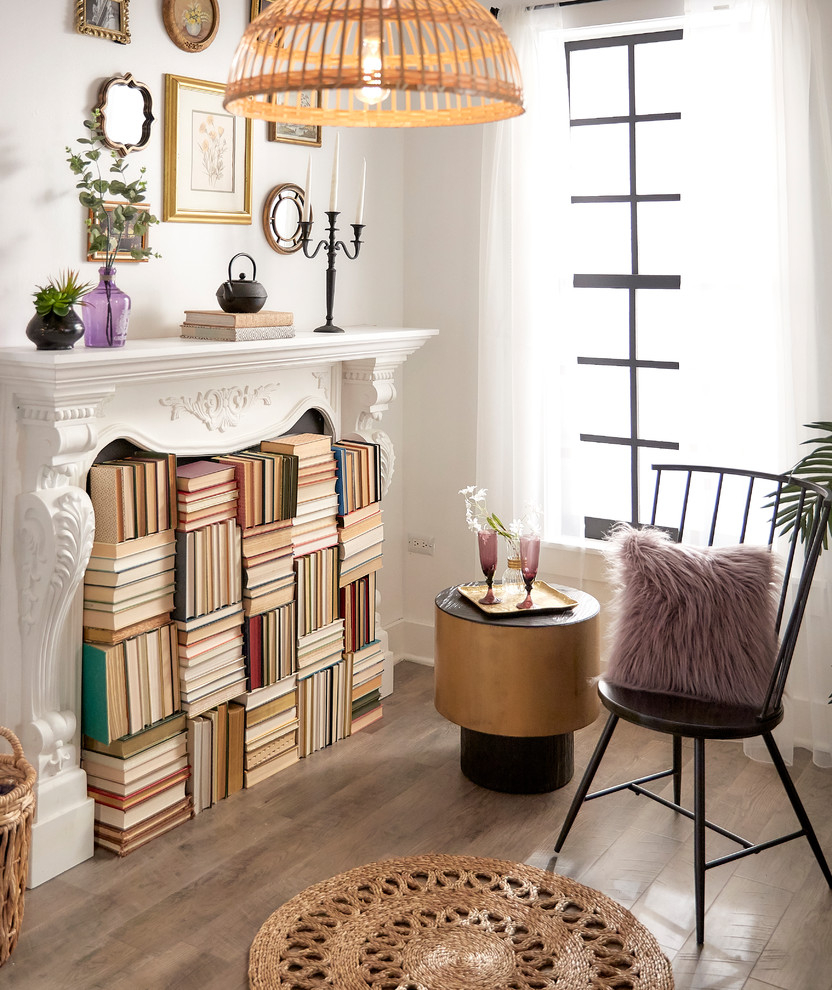 Small eclectic home office in Portland with a library, white walls, light hardwood floors, a standard fireplace, a plaster fireplace surround and brown floor.