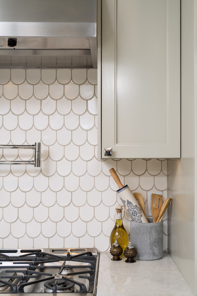 Inspiration for a large transitional u-shaped porcelain tile enclosed kitchen remodel with an undermount sink, shaker cabinets, gray cabinets, quartz countertops, white backsplash, ceramic backsplash, stainless steel appliances and a peninsula