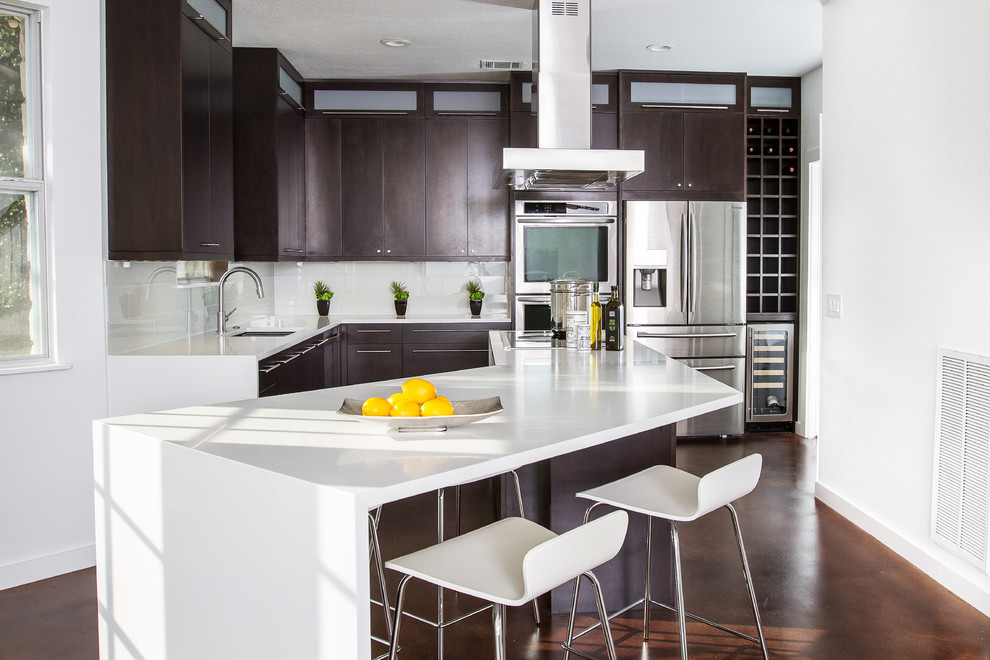 This is an example of a mid-sized modern l-shaped open plan kitchen in Austin with an undermount sink, flat-panel cabinets, dark wood cabinets, quartz benchtops, white splashback, glass tile splashback, stainless steel appliances, concrete floors and with island.