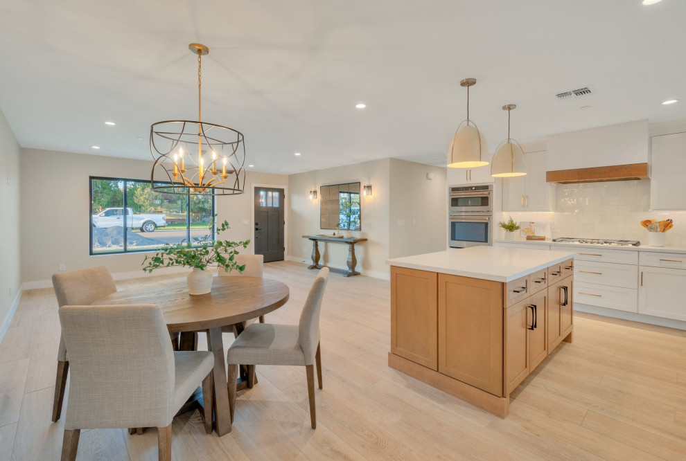 Large transitional l-shaped porcelain tile and beige floor kitchen pantry photo in Phoenix with a farmhouse sink, shaker cabinets, white cabinets, quartz countertops, white backsplash, ceramic backsplash, stainless steel appliances, an island and white countertops