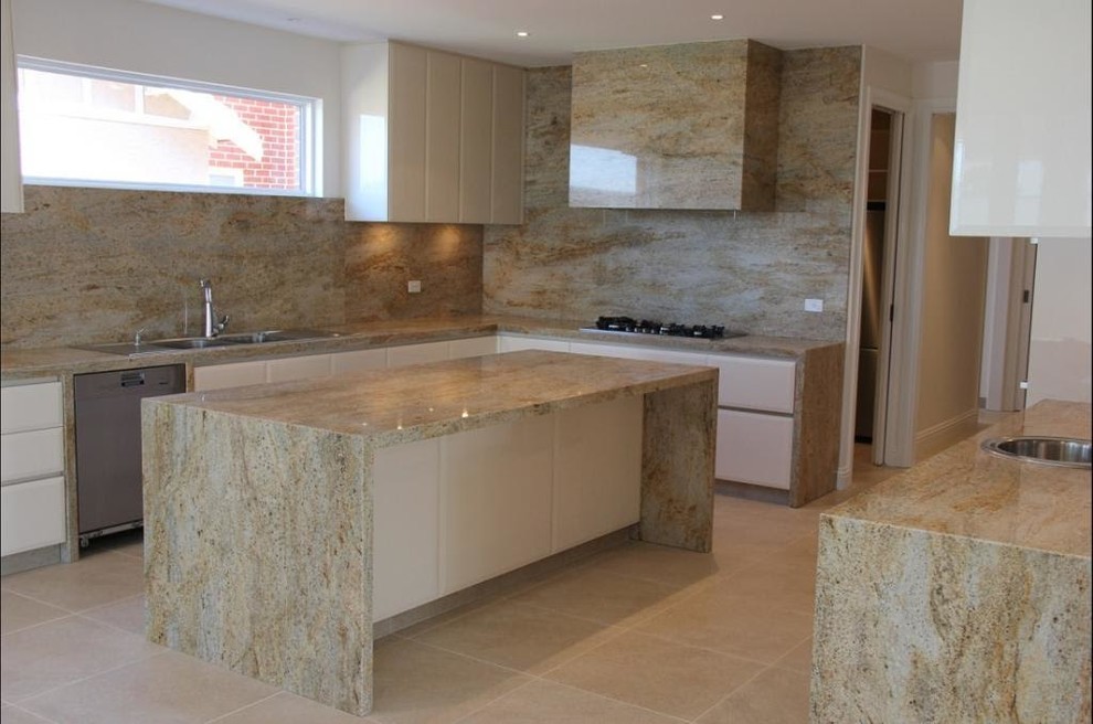 Kitchen - mid-sized modern l-shaped ceramic tile and beige floor kitchen idea with a double-bowl sink, flat-panel cabinets, white cabinets, granite countertops, beige backsplash, stone slab backsplash and an island