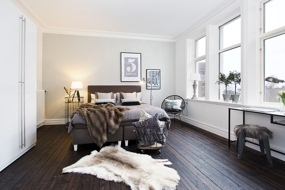 This is an example of a large scandinavian master bedroom in Malmo with white walls, dark hardwood floors and no fireplace.