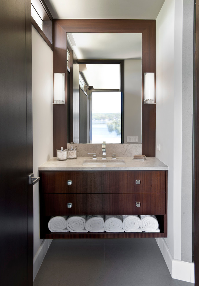 Small contemporary powder room in Detroit with an undermount sink, flat-panel cabinets, marble benchtops, gray tile, white walls, ceramic floors and dark wood cabinets.