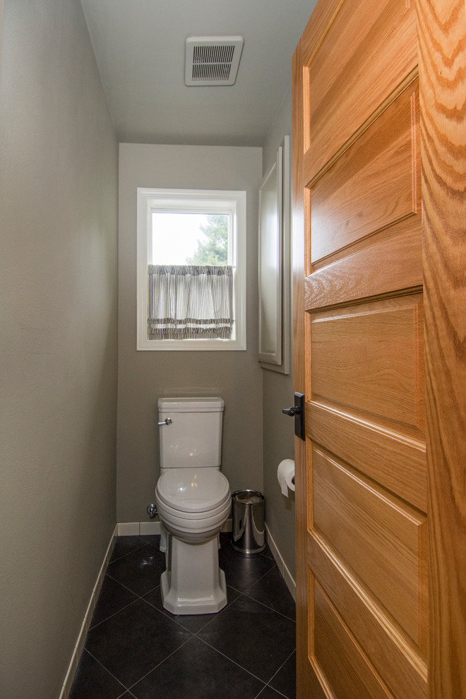 This is an example of a medium sized classic cloakroom in Seattle with freestanding cabinets, distressed cabinets, a one-piece toilet, white tiles, ceramic tiles, grey walls, porcelain flooring, a submerged sink, quartz worktops and black floors.