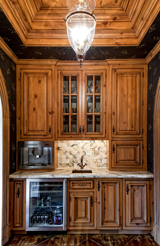 This is an example of a mid-sized traditional single-wall wet bar in New York with a drop-in sink, glass-front cabinets, medium wood cabinets, granite benchtops and dark hardwood floors.