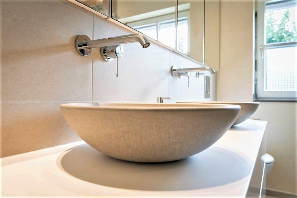 Mittelgroßes Modernes Duschbad mit flächenbündigen Schrankfronten, beigen Schränken, Einbaubadewanne, Duschbadewanne, beigen Fliesen, Beton-Waschbecken/Waschtisch, beigem Boden, Falttür-Duschabtrennung und weißer Waschtischplatte in Düsseldorf