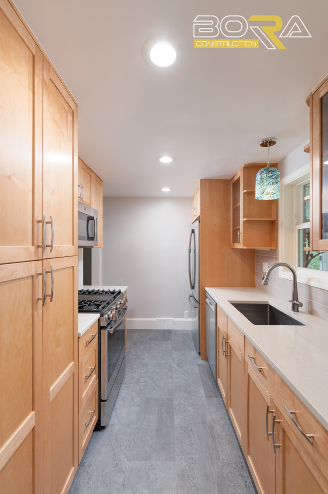 This is an example of a small transitional galley separate kitchen in Seattle with an undermount sink, shaker cabinets, medium wood cabinets, quartz benchtops, grey splashback, ceramic splashback, stainless steel appliances, laminate floors, no island, grey floor and grey benchtop.