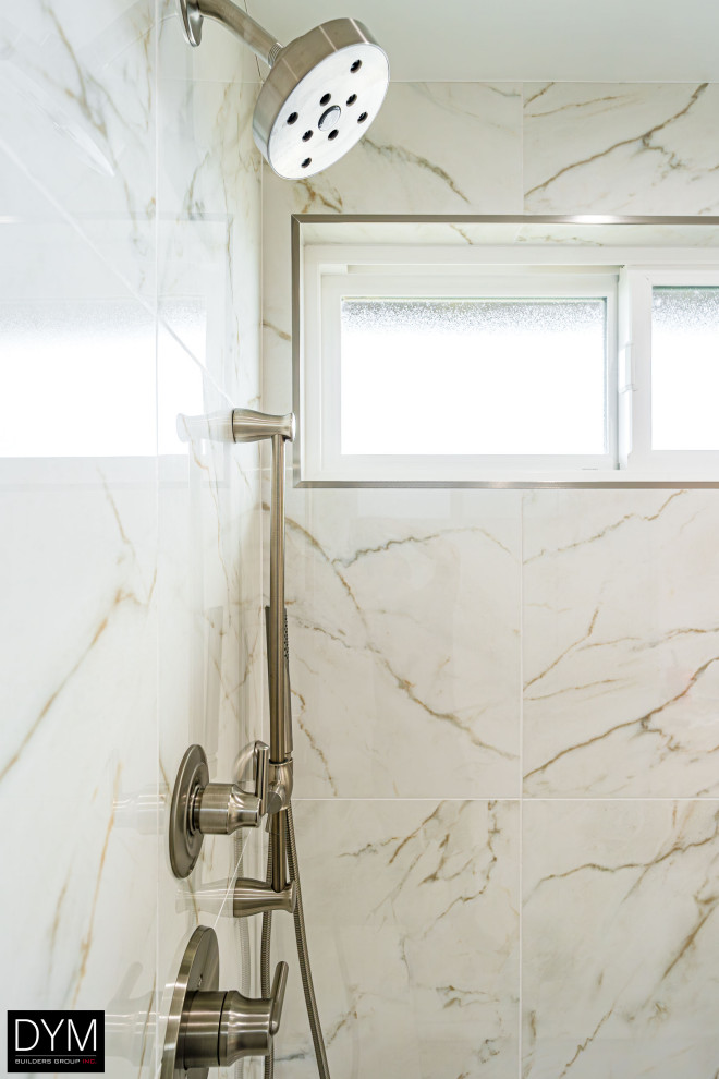 Modern inredning av ett stort vit vitt en-suite badrum, med luckor med profilerade fronter, vita skåp, en dusch i en alkov, en toalettstol med hel cisternkåpa, vit kakel, marmorkakel, vita väggar, marmorgolv, ett nedsänkt handfat, bänkskiva i akrylsten, vitt golv och dusch med gångjärnsdörr