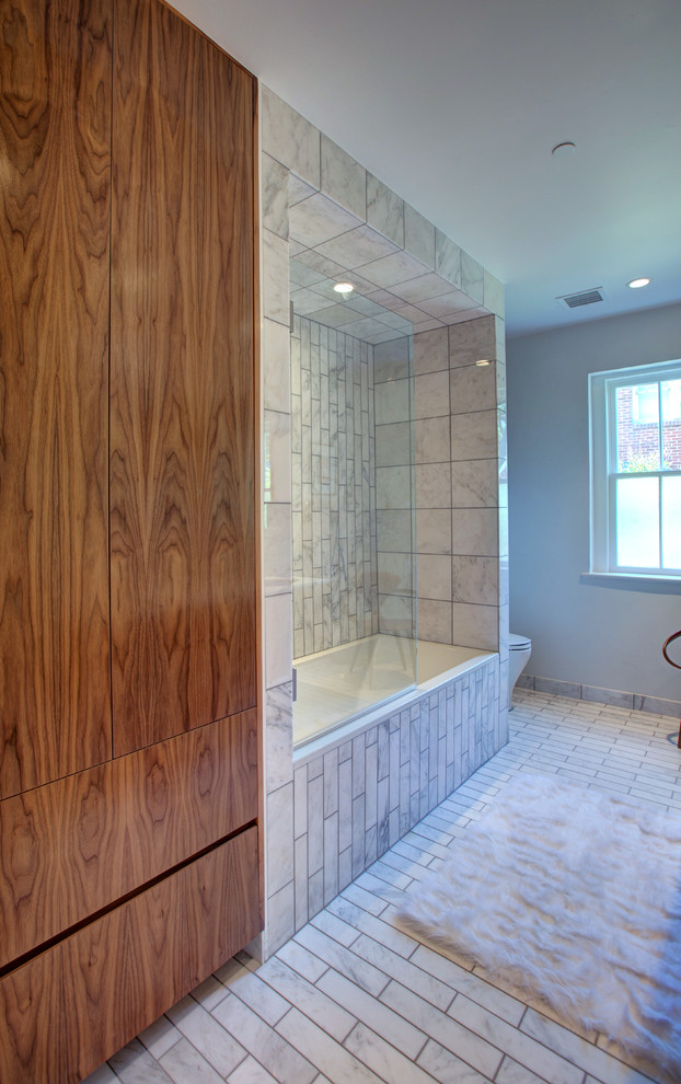 Inspiration for a mid-sized contemporary 3/4 bathroom in Oklahoma City with an undermount sink, flat-panel cabinets, medium wood cabinets, engineered quartz benchtops, a drop-in tub, a shower/bathtub combo, a wall-mount toilet, white tile, stone tile, white walls and marble floors.