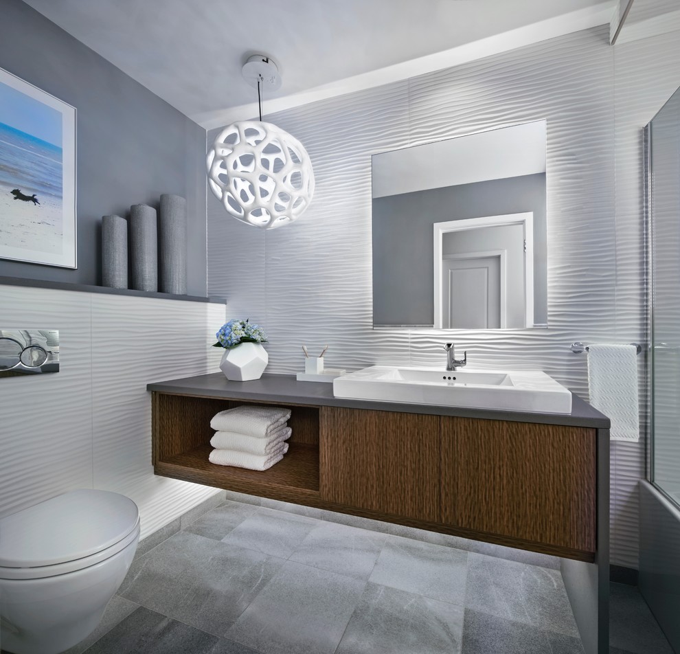 Small modern 3/4 bathroom in Detroit with flat-panel cabinets, brown cabinets, an alcove tub, an alcove shower, a wall-mount toilet, white tile, white walls, marble floors, a vessel sink, concrete benchtops, grey floor, a hinged shower door, porcelain tile and grey benchtops.