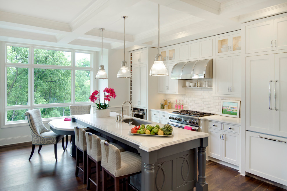Inspiration for a transitional dark wood floor eat-in kitchen remodel in Minneapolis with an undermount sink, white cabinets, solid surface countertops, white backsplash, an island, shaker cabinets, subway tile backsplash and paneled appliances