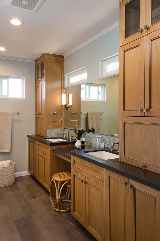 Photo of a mid-sized transitional master bathroom in San Francisco with beaded inset cabinets, light wood cabinets, blue tile, glass sheet wall, porcelain floors, a drop-in sink, engineered quartz benchtops, grey floor and black benchtops.