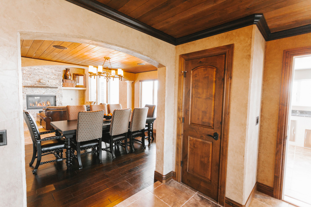 Transitional dark wood floor dining room photo with beige walls, a hanging fireplace and a stone fireplace
