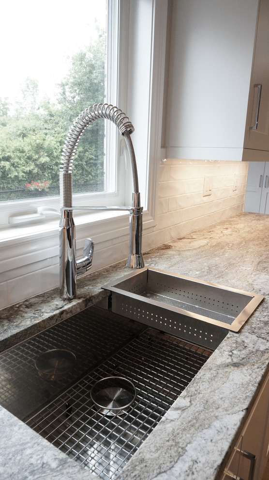 Inspiration for a large transitional u-shaped kitchen remodel in Toronto with a single-bowl sink, shaker cabinets, white cabinets, granite countertops, white backsplash, porcelain backsplash, stainless steel appliances and an island