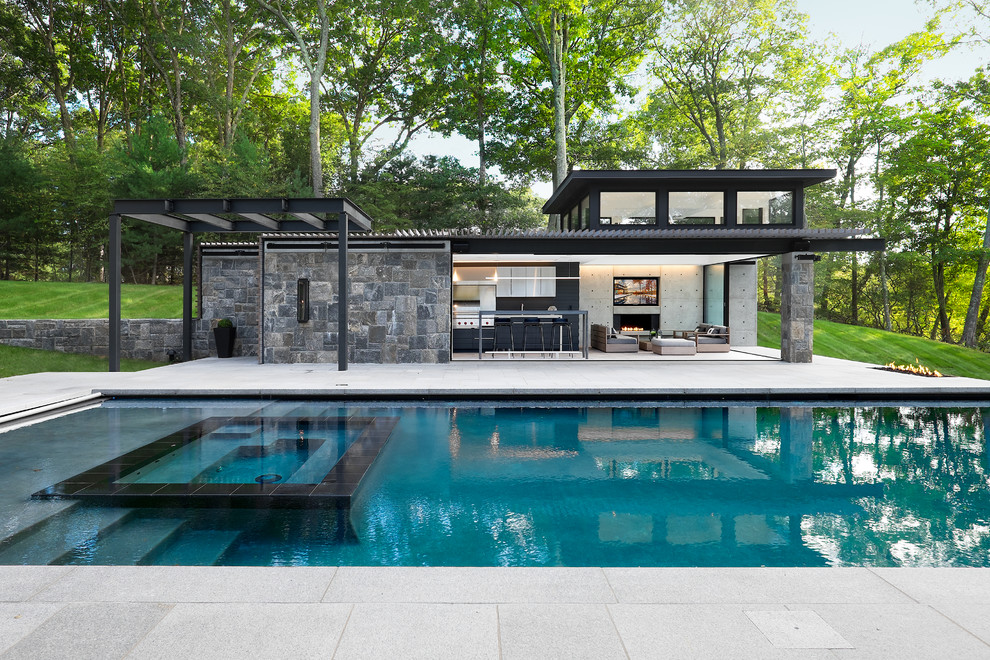 Contemporary rectangular pool in New York with a hot tub and concrete pavers.