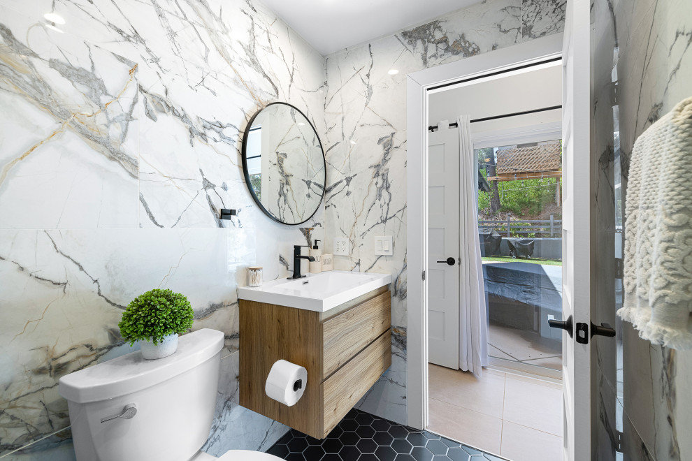 Пример оригинального дизайна: детская ванная комната среднего размера в стиле модернизм с плоскими фасадами, светлыми деревянными фасадами, душем в нише, унитазом-моноблоком, черно-белой плиткой, керамогранитной плиткой, белыми стенами, полом из керамогранита, монолитной раковиной, столешницей из искусственного камня, черным полом, душем с раздвижными дверями, белой столешницей, тумбой под одну раковину и подвесной тумбой