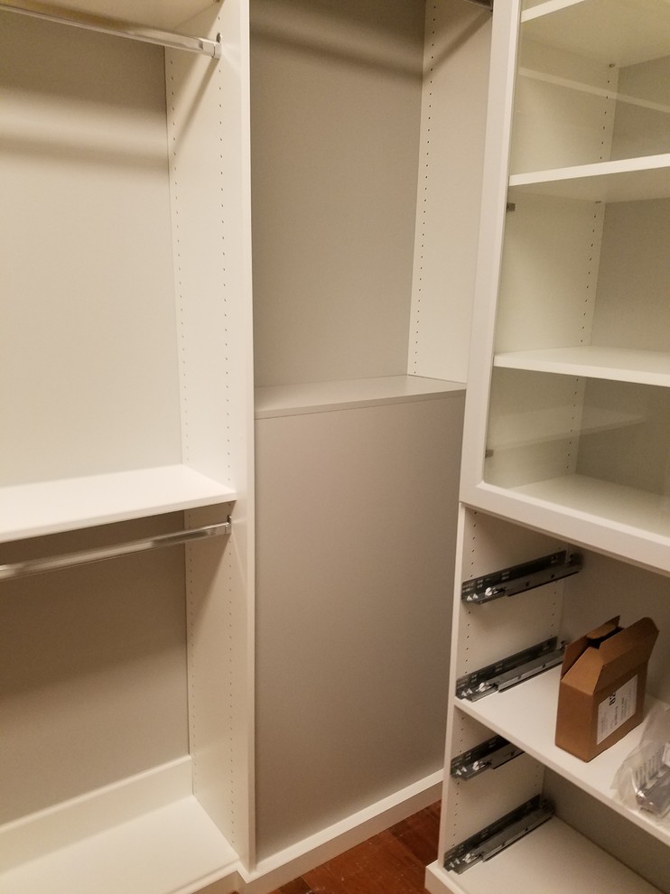 This is an example of a small transitional gender-neutral built-in wardrobe in Louisville with open cabinets, white cabinets, medium hardwood floors and brown floor.