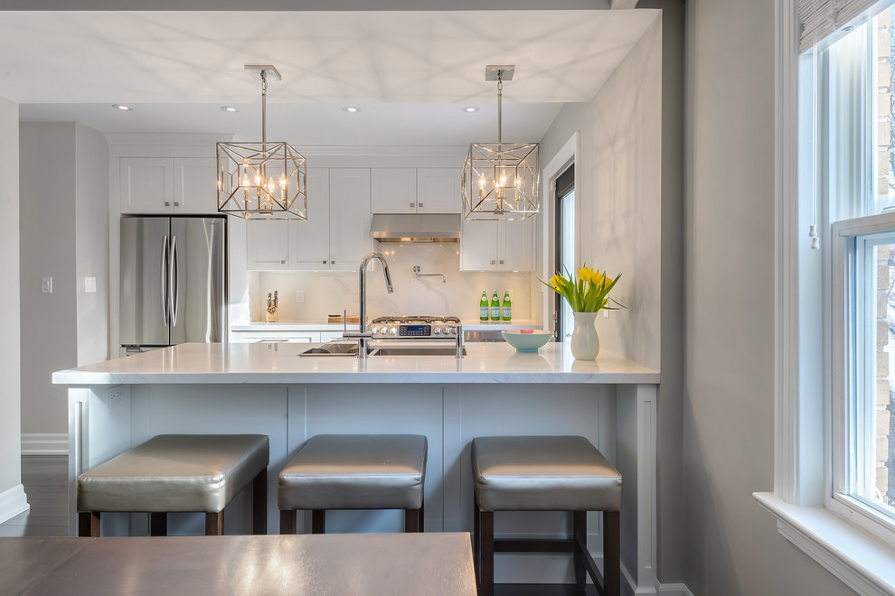 Inspiration for a small transitional galley dark wood floor eat-in kitchen remodel in Toronto with an undermount sink, shaker cabinets, white cabinets, quartz countertops, white backsplash, stone slab backsplash, stainless steel appliances and an island