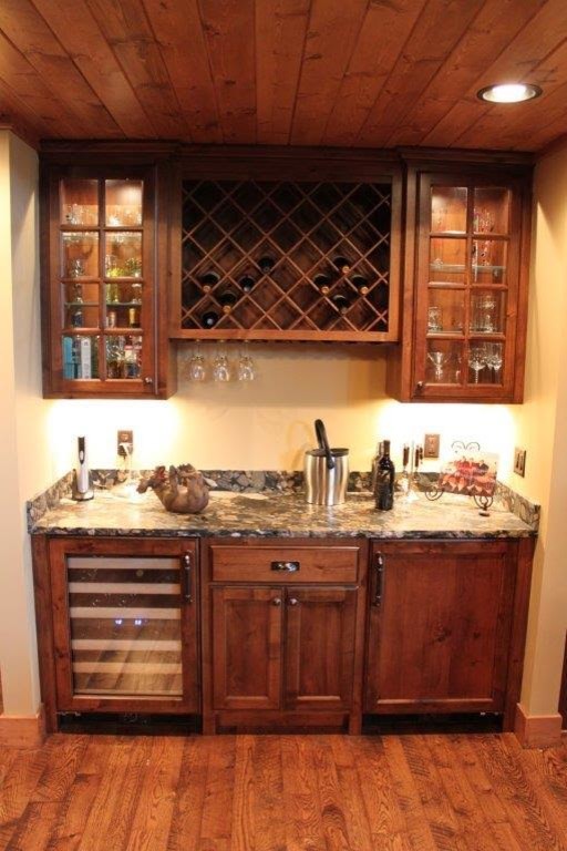This is an example of a small country single-wall home bar in Minneapolis with shaker cabinets, medium wood cabinets, granite benchtops, medium hardwood floors and brown floor.