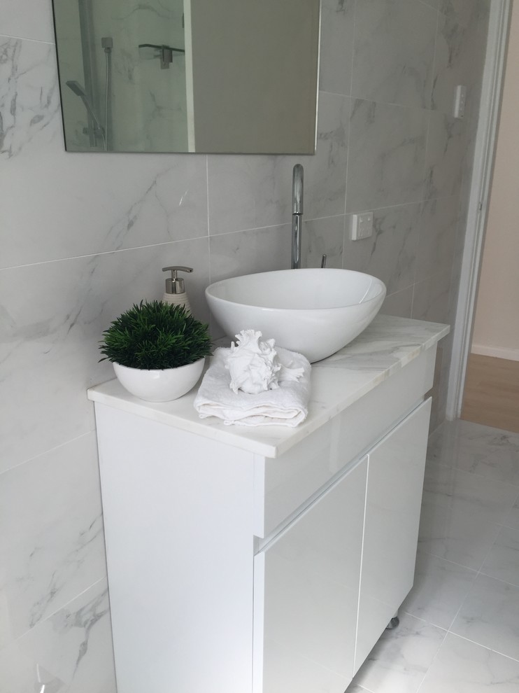 This is an example of a small contemporary 3/4 bathroom in Sydney with flat-panel cabinets, white cabinets, white tile, marble, marble benchtops, a corner shower, white walls, marble floors, a vessel sink, white floor and a hinged shower door.