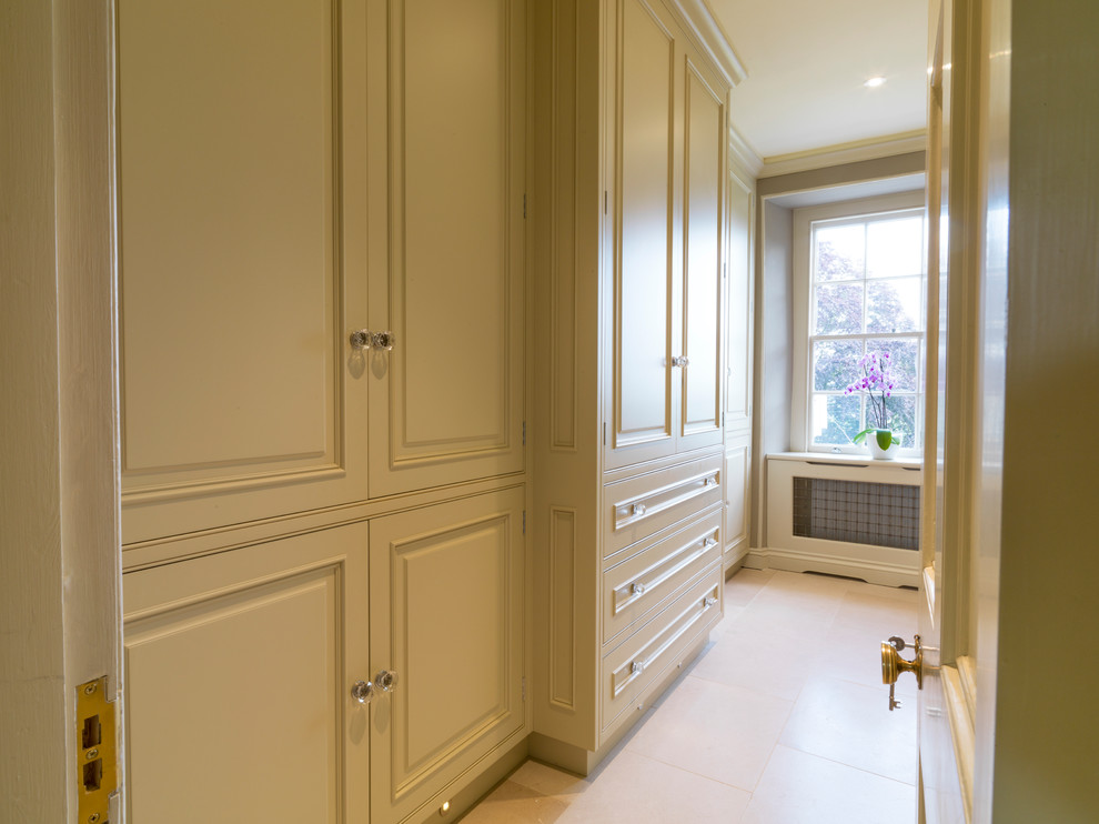 This is an example of a large traditional storage and wardrobe in Other with raised-panel cabinets, green cabinets and limestone floors.