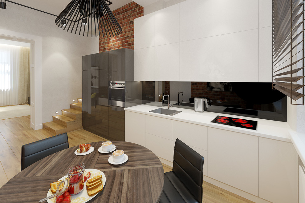 Eat-in kitchen - mid-sized contemporary single-wall light wood floor eat-in kitchen idea in London with a drop-in sink, flat-panel cabinets, white cabinets, glass tile backsplash and paneled appliances