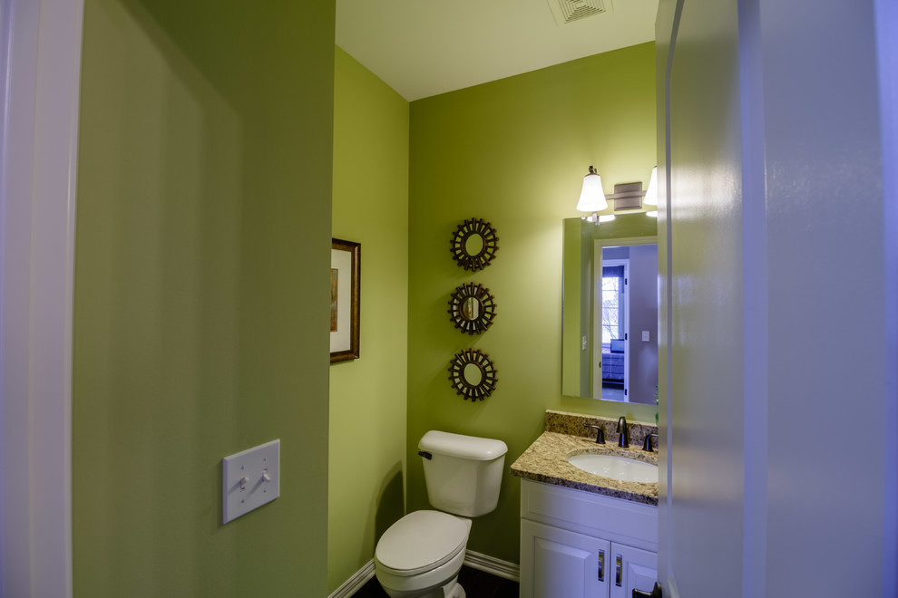 Design ideas for a mid-sized traditional powder room in Detroit with shaker cabinets, white cabinets, a one-piece toilet, green walls, medium hardwood floors, an undermount sink, granite benchtops and brown floor.