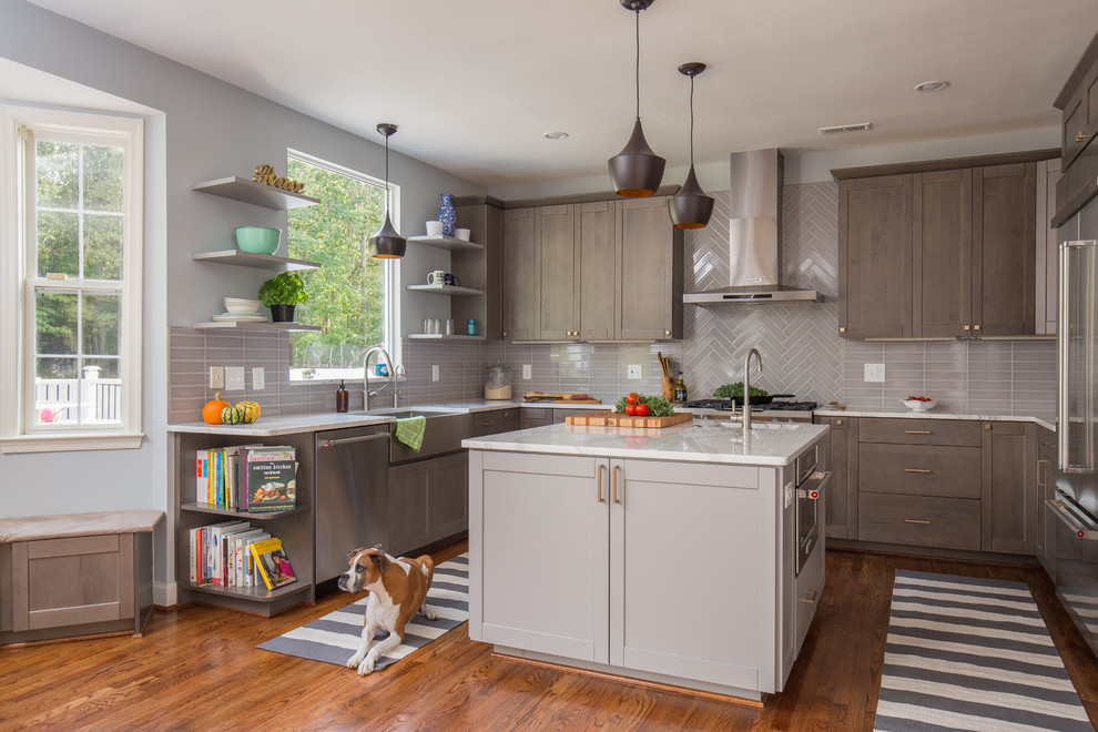 Photo of a mid-sized contemporary u-shaped eat-in kitchen in DC Metro with an undermount sink, shaker cabinets, grey cabinets, grey splashback, porcelain splashback, stainless steel appliances, medium hardwood floors, with island and quartz benchtops.