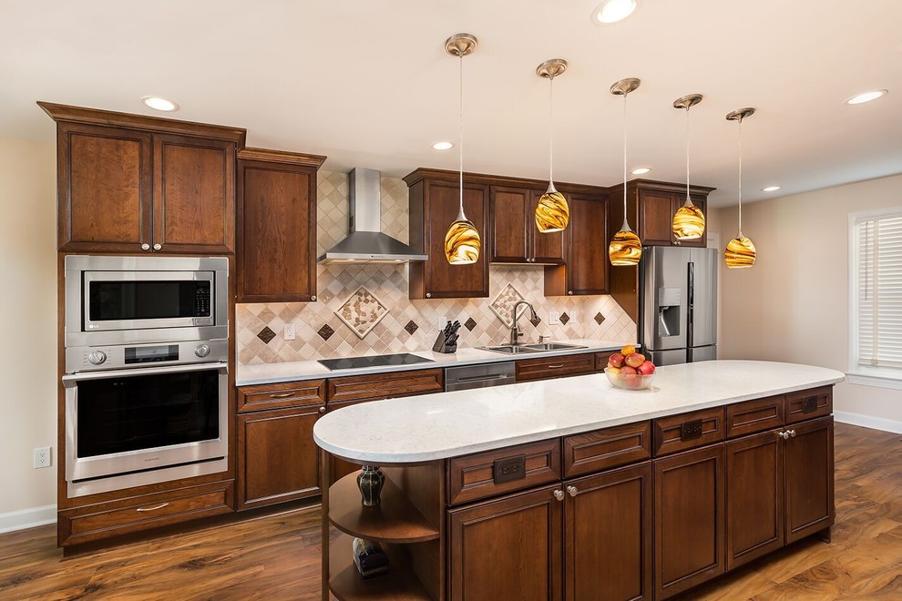 This is an example of a mid-sized transitional single-wall eat-in kitchen in DC Metro with a double-bowl sink, recessed-panel cabinets, dark wood cabinets, quartz benchtops, beige splashback, stone tile splashback, stainless steel appliances, vinyl floors, with island and brown floor.