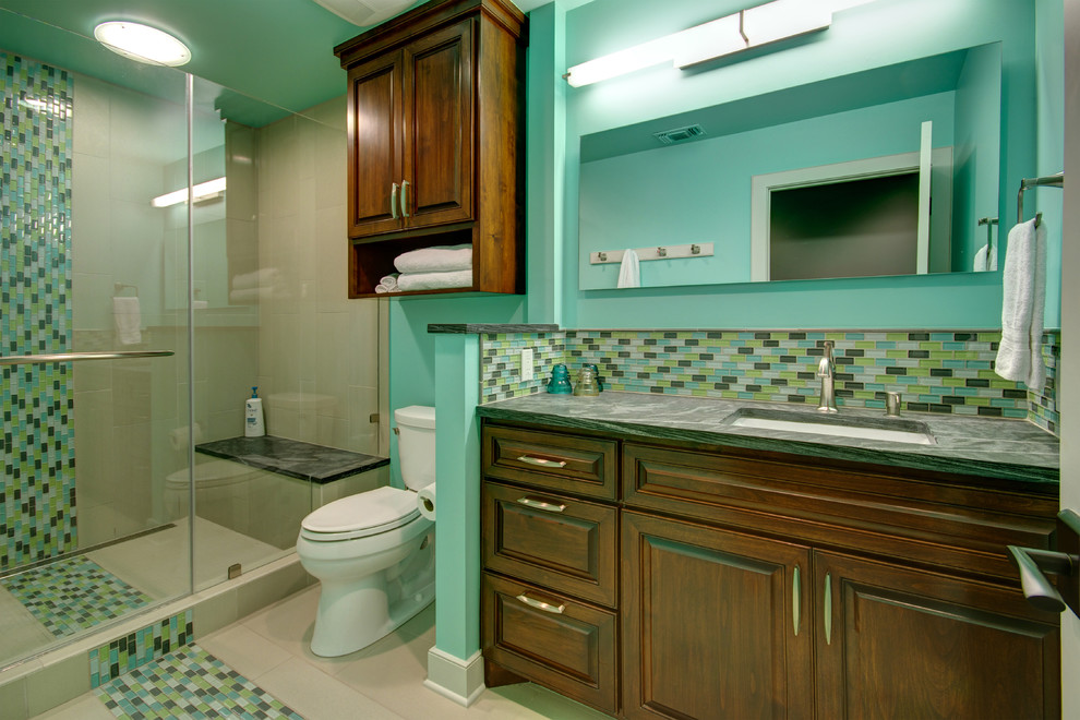 Inspiration for a mid-sized contemporary bathroom in Austin with an undermount sink, raised-panel cabinets, medium wood cabinets, soapstone benchtops, an alcove shower, multi-coloured tile, glass tile, green walls, porcelain floors and green benchtops.