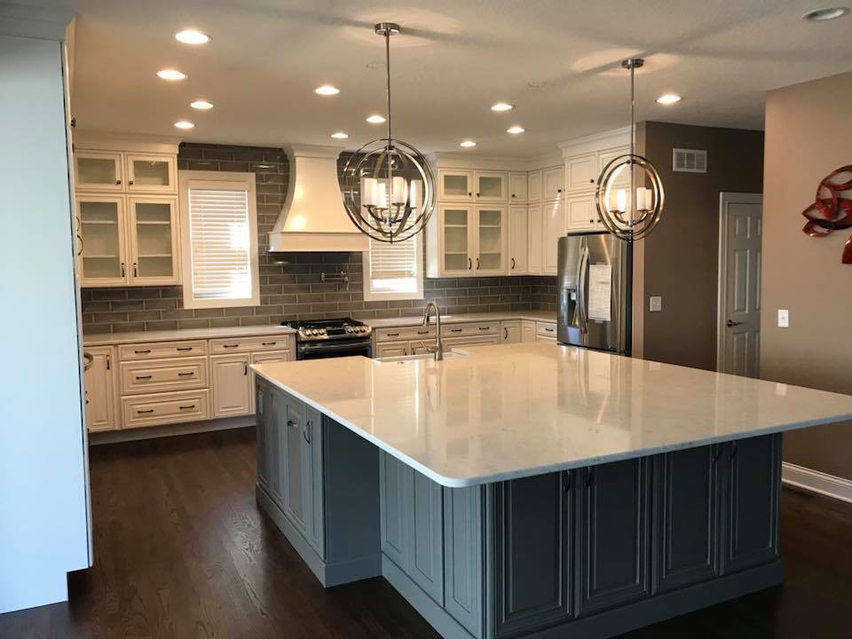Inspiration for a mid-sized transitional u-shaped medium tone wood floor and brown floor open concept kitchen remodel in Cincinnati with a farmhouse sink, glass-front cabinets, white cabinets, quartz countertops, gray backsplash, subway tile backsplash, stainless steel appliances, an island and white countertops