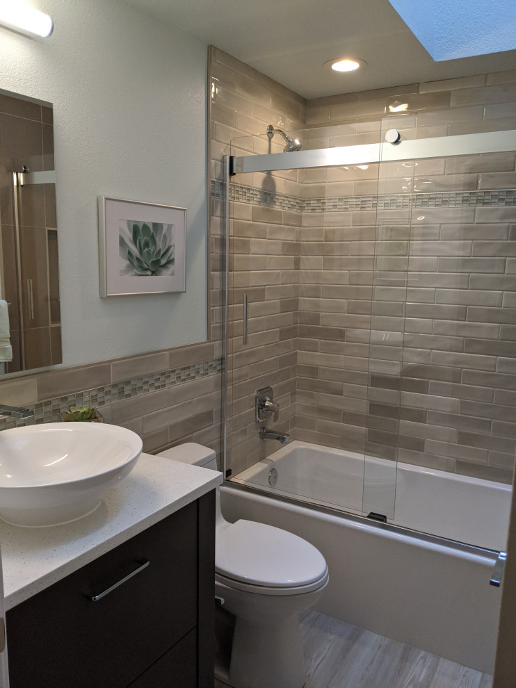 Photo of a small transitional kids bathroom in Seattle with furniture-like cabinets, brown cabinets, a drop-in tub, a shower/bathtub combo, a one-piece toilet, brown tile, mosaic tile, green walls, porcelain floors, a vessel sink, engineered quartz benchtops, brown floor, a sliding shower screen and white benchtops.