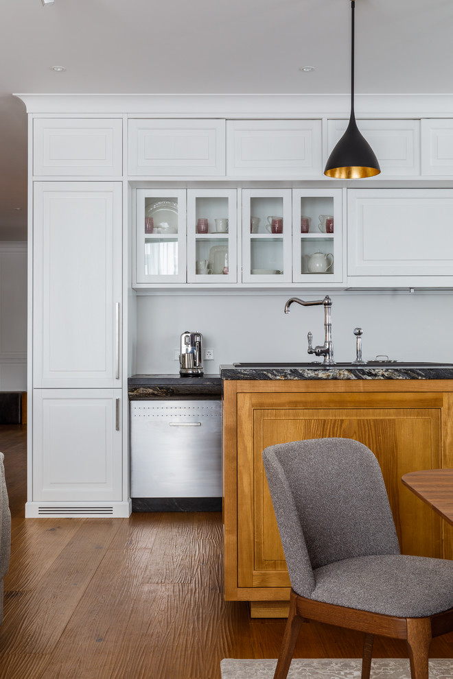 Large contemporary single-wall eat-in kitchen in Moscow with an undermount sink, white cabinets, stone slab splashback, medium hardwood floors, with island, brown floor, grey benchtop, raised-panel cabinets and white splashback.