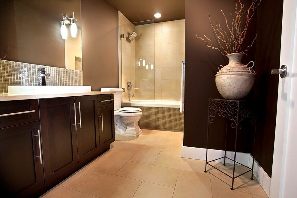 Photo of a large arts and crafts bathroom in Vancouver with a drop-in sink, recessed-panel cabinets, dark wood cabinets, granite benchtops, a drop-in tub, a shower/bathtub combo, a one-piece toilet, green tile, subway tile, brown walls and ceramic floors.