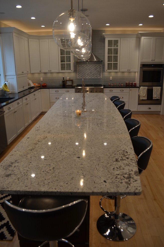 Eat-in kitchen - mid-sized transitional single-wall light wood floor and yellow floor eat-in kitchen idea with an undermount sink, shaker cabinets, white cabinets, quartz countertops, gray backsplash, glass tile backsplash, stainless steel appliances and an island