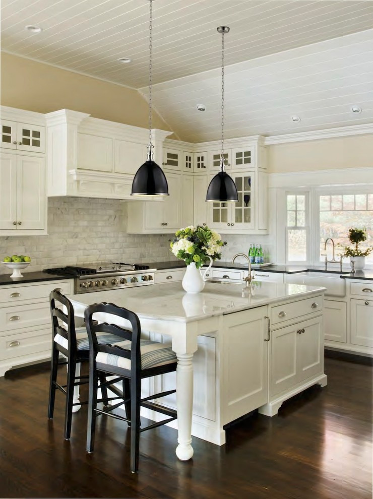 Design ideas for a large contemporary l-shaped eat-in kitchen in Providence with a farmhouse sink, white cabinets, marble benchtops, white splashback, ceramic splashback, stainless steel appliances, dark hardwood floors, with island and beaded inset cabinets.