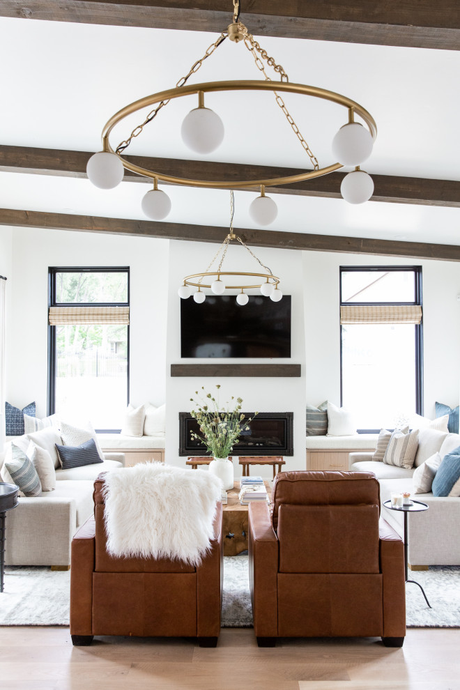 Inspiration for a transitional open concept living room in Salt Lake City with white walls, medium hardwood floors, a ribbon fireplace, a wall-mounted tv, brown floor and exposed beam.