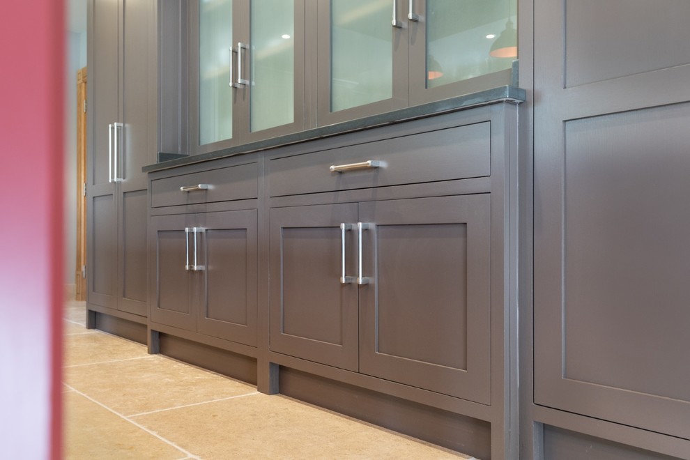 Photo of an expansive traditional galley eat-in kitchen in Hertfordshire with a drop-in sink, recessed-panel cabinets, brown cabinets, quartzite benchtops, panelled appliances, terra-cotta floors, with island, beige floor and grey benchtop.