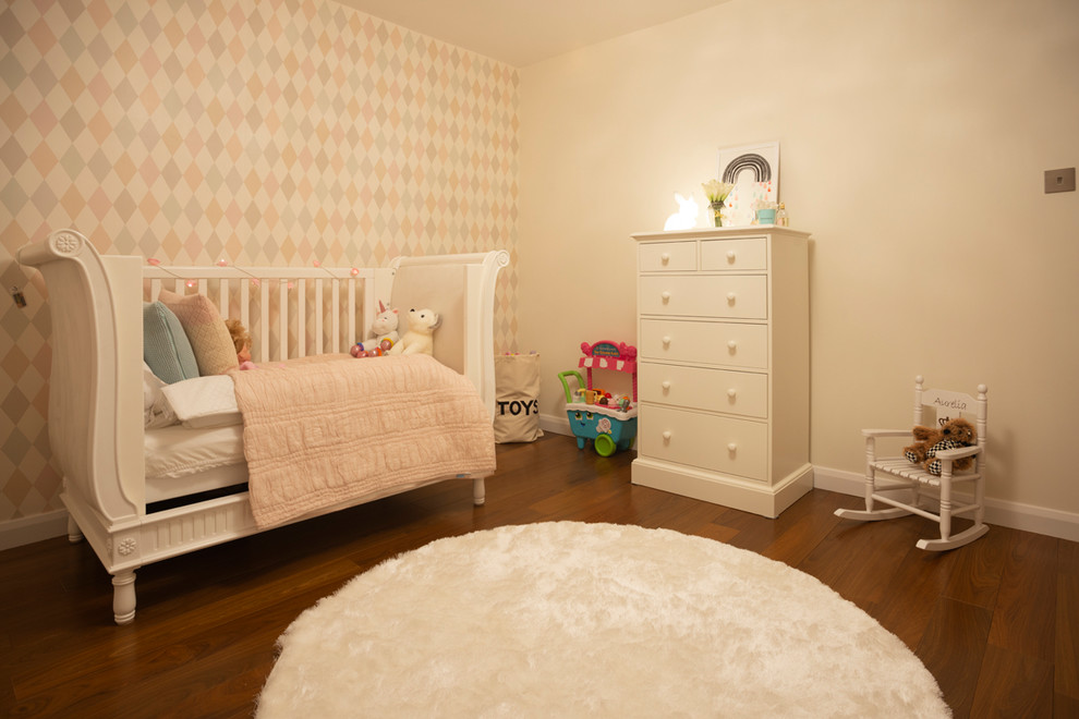 Photo of a mid-sized contemporary nursery for girls in Surrey with beige walls, medium hardwood floors and brown floor.